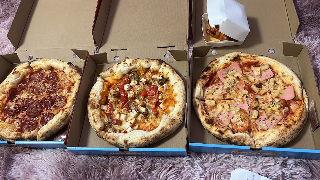 Three delicious pizzas and a side dish in takeout boxes from Now Pizza.