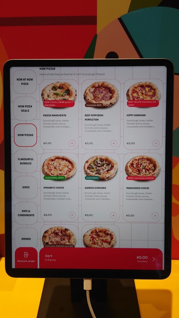 A digital menu display for Now Pizza, showcasing various pizza options and prices.