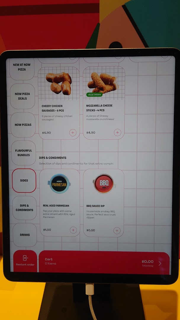 A digital self-ordering kiosk displaying menu items, prices, and categories for Now Pizza.