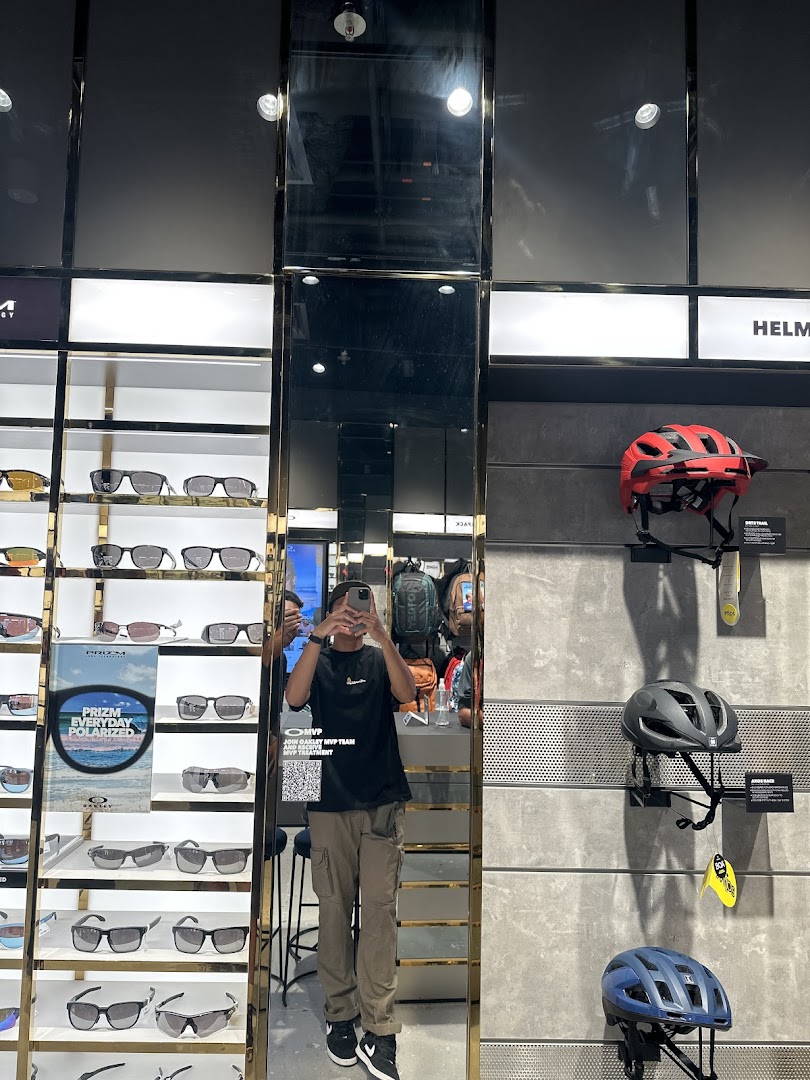 Interior view of Oakley Funan showcasing sunglasses, helmets, and a customer reflection in a large mirror.