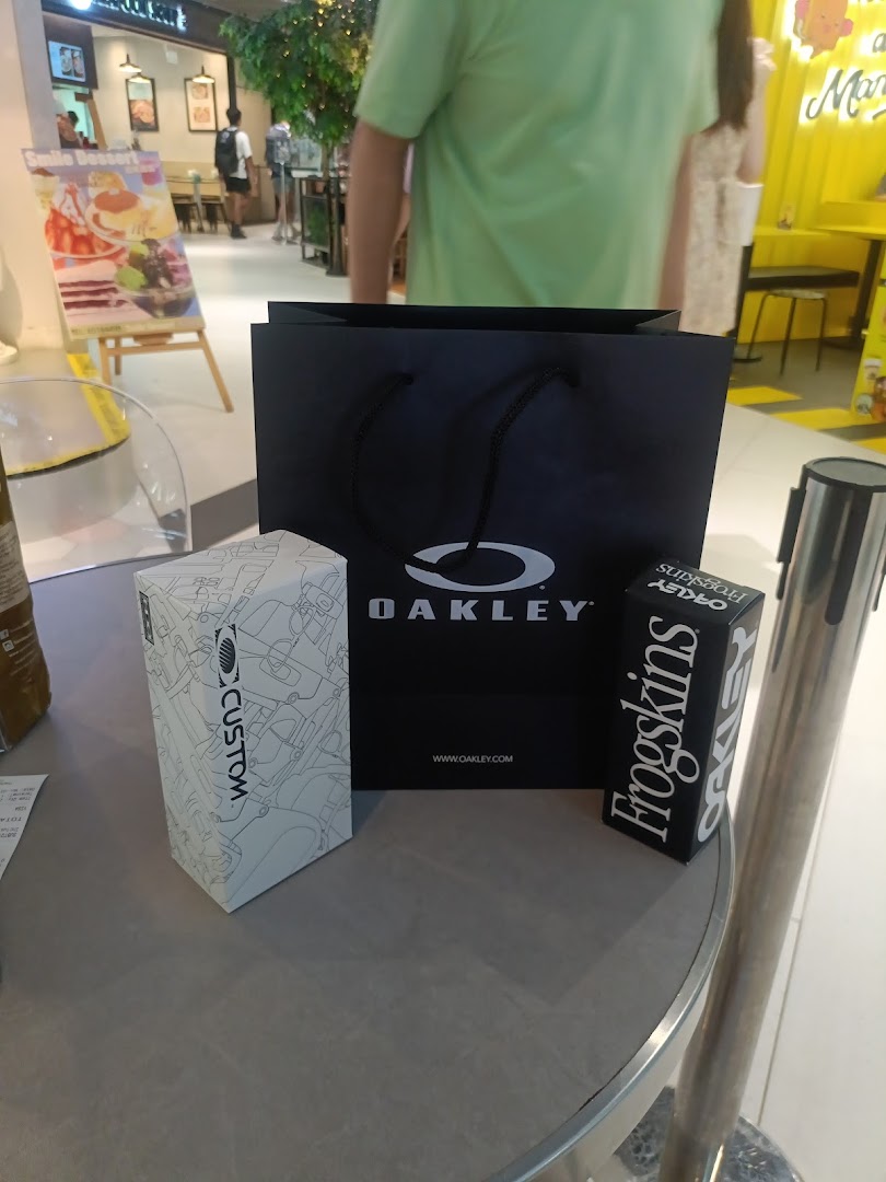 An Oakley shopping bag and product boxes, including 'Frogskins' and 'Custom', on a table.