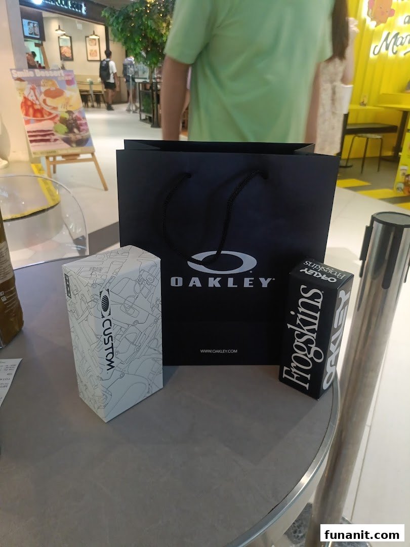 An Oakley shopping bag and product boxes, including 'Frogskins' and 'Custom', on a table.