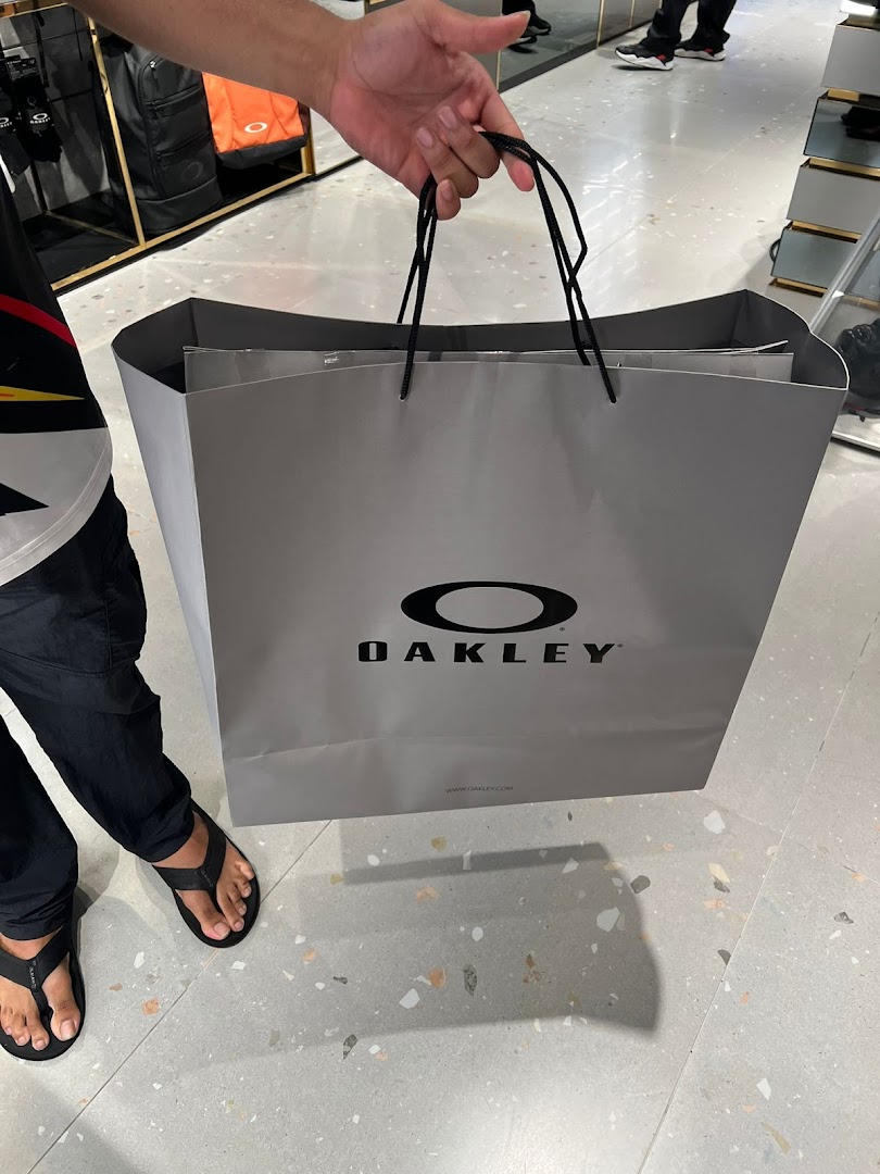 A shopper holds a grey Oakley shopping bag inside the store, showcasing a recent purchase.