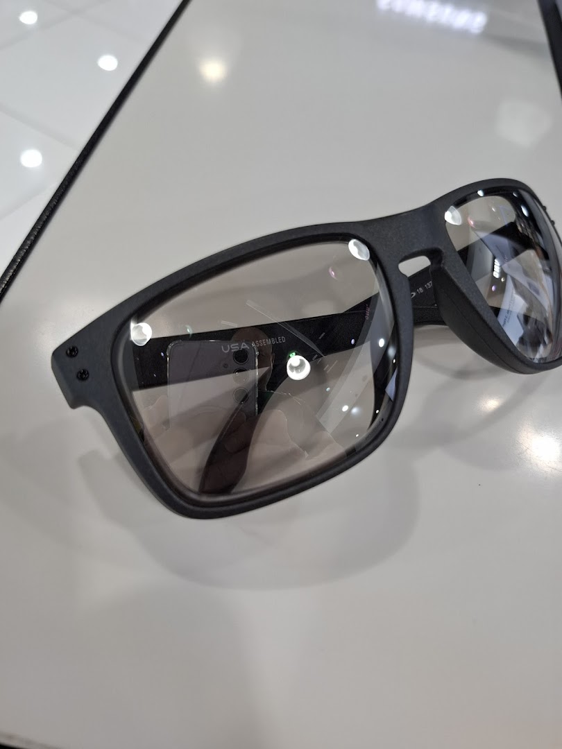 A close-up of a pair of black-framed Oakley sunglasses with clear lenses on display.