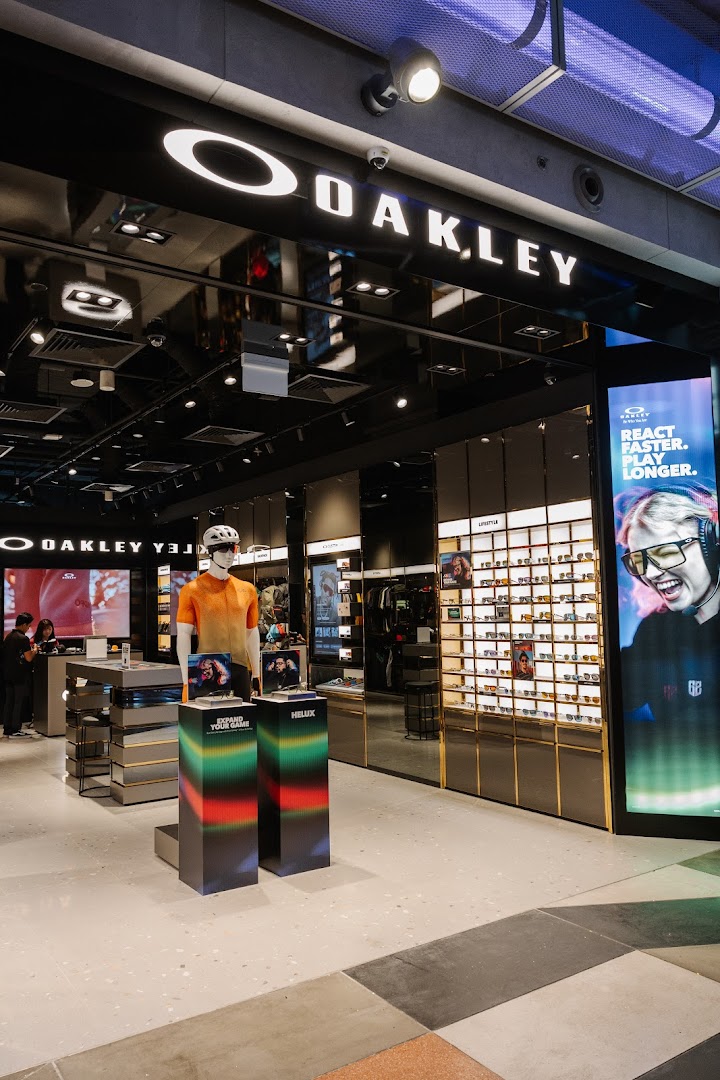 Interior view of the Oakley store, featuring eyewear displays, activewear on a mannequin, and a large digital screen.