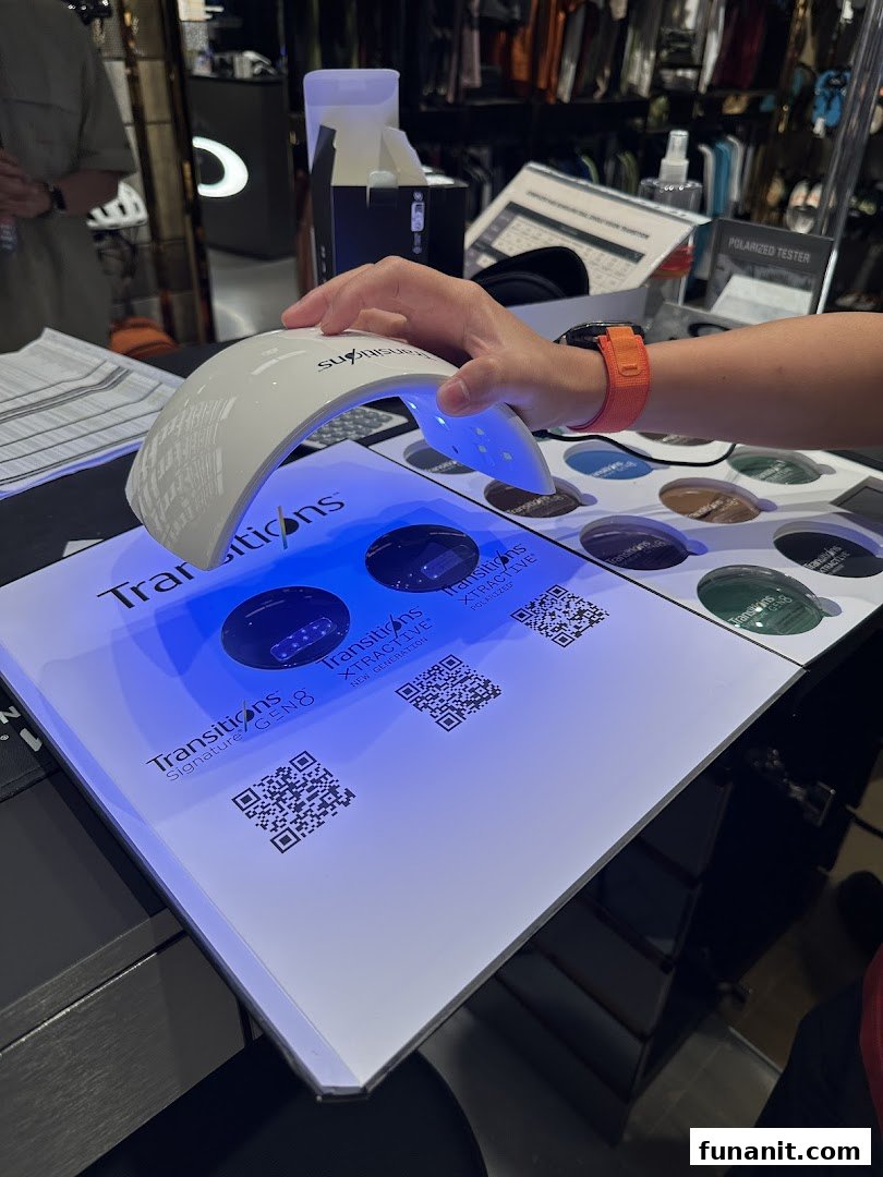 A hand demonstrates Transitions lens technology with a UV light at an Oakley store display.