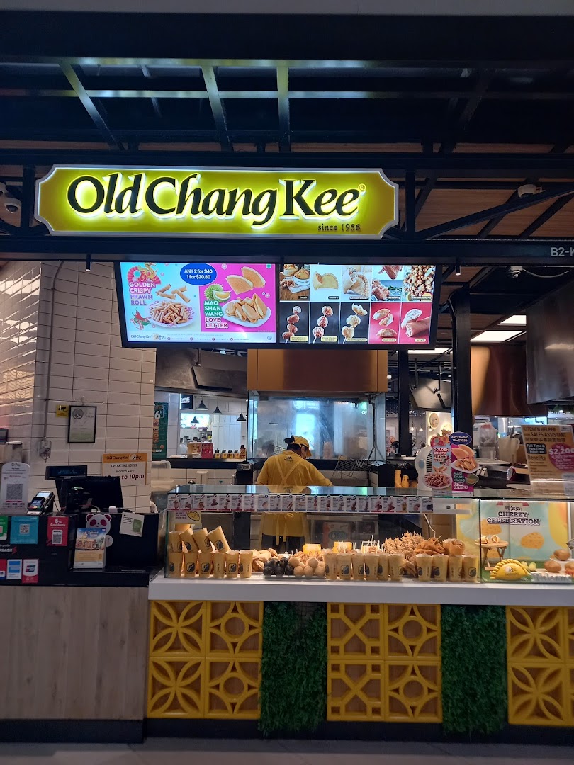 A vibrant interior shot of Old Chang Kee, showcasing its fried snacks display and digital menu boards.