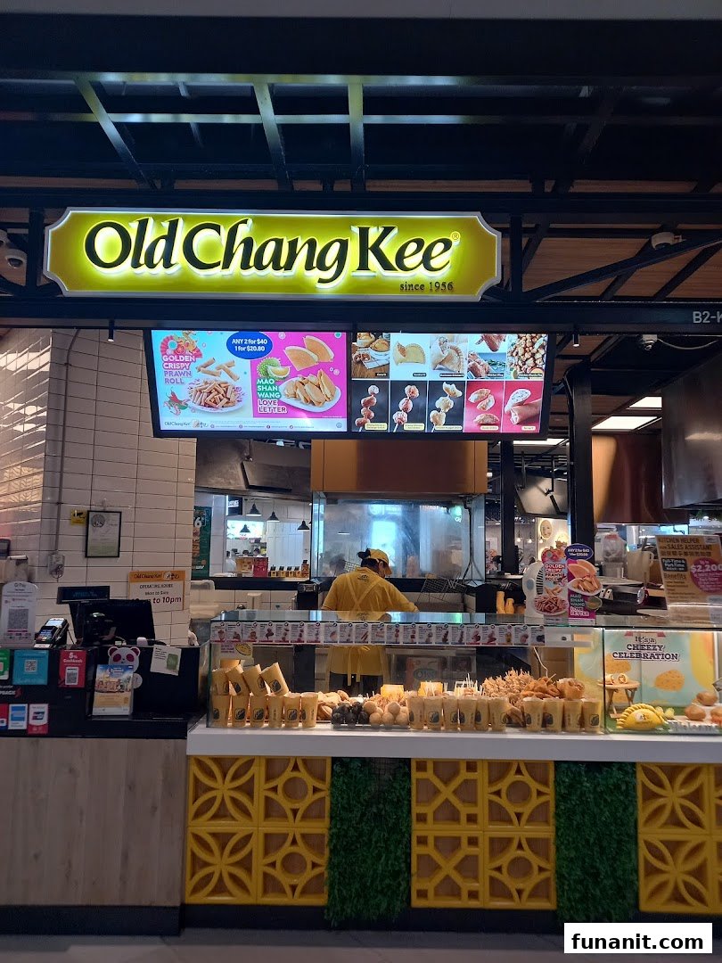 A vibrant interior shot of Old Chang Kee, showcasing its fried snacks display and digital menu boards.