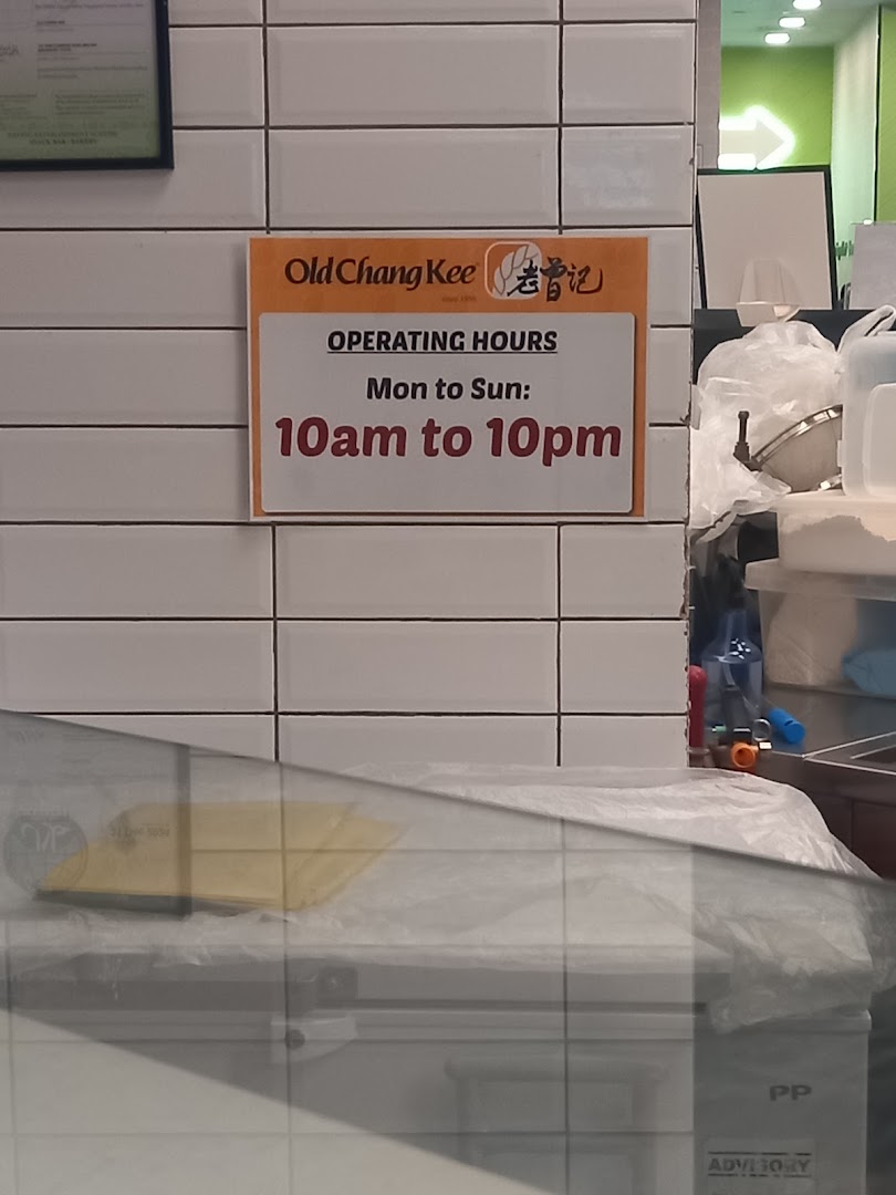 A sign at Old Chang Kee displaying the shop's daily operating hours.