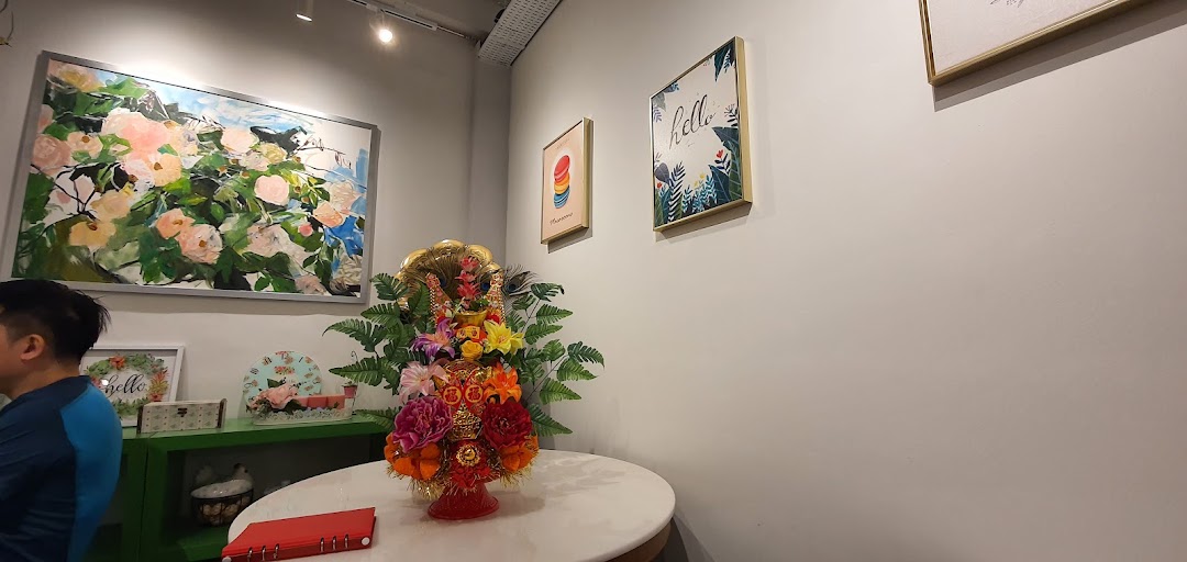 An interior view of a shop featuring decorative artwork, a floral centerpiece, and a customer.