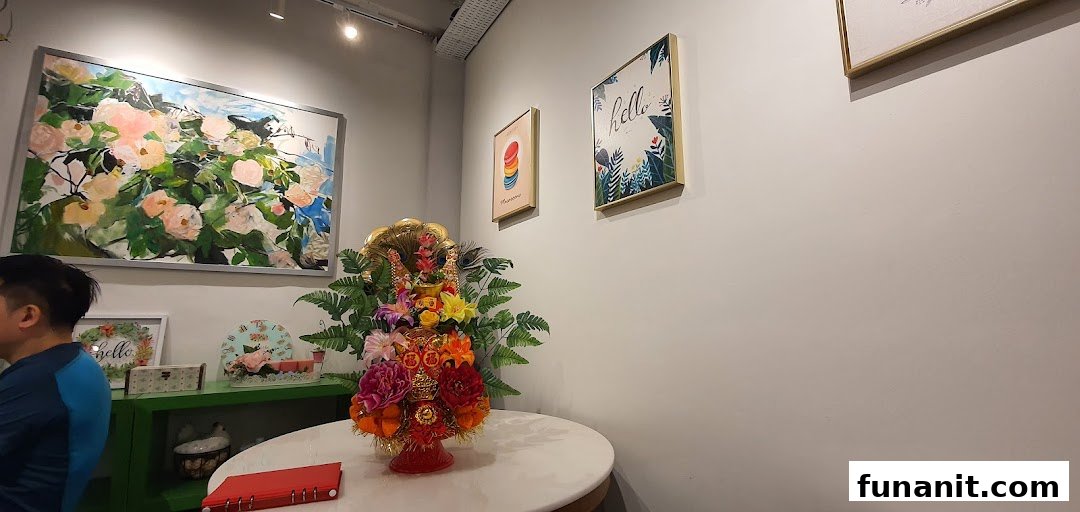 An interior view of a shop featuring decorative artwork, a floral centerpiece, and a customer.