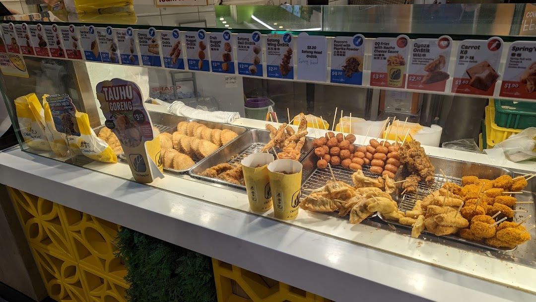 A vibrant display counter showcasing Old Chang Kee's variety of fried snacks and pastries with price tags.