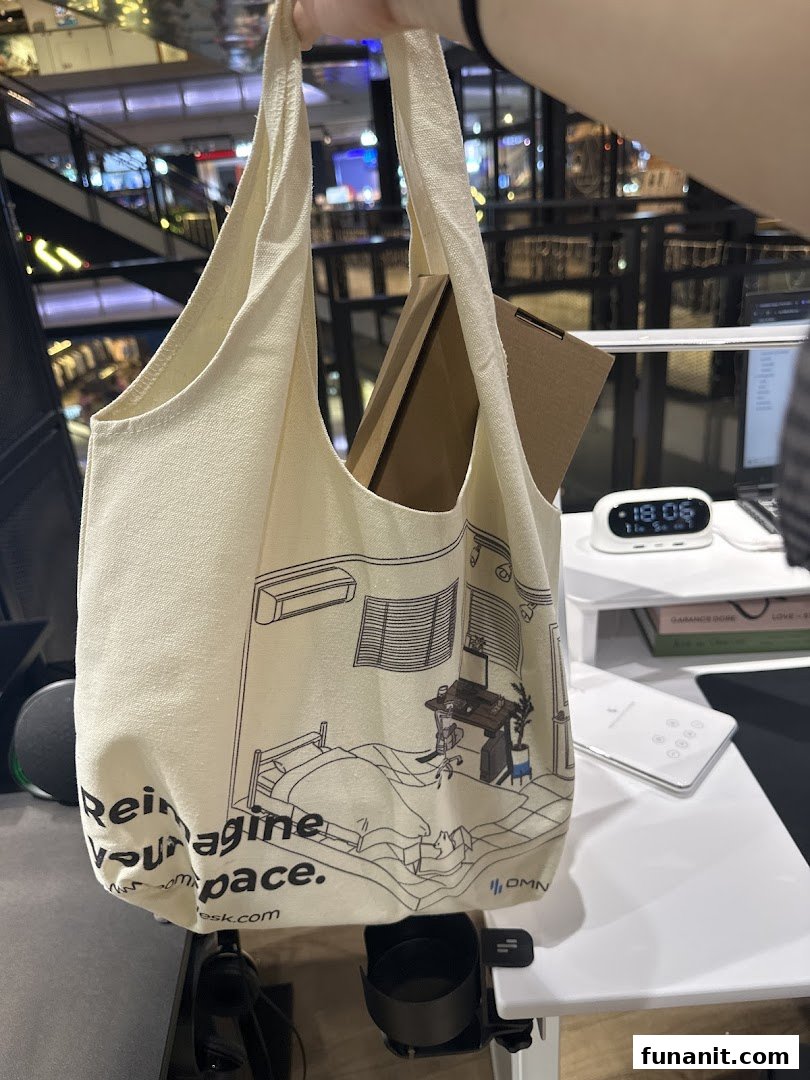 A person holds an Omnidesk branded tote bag featuring a home office illustration inside the store.