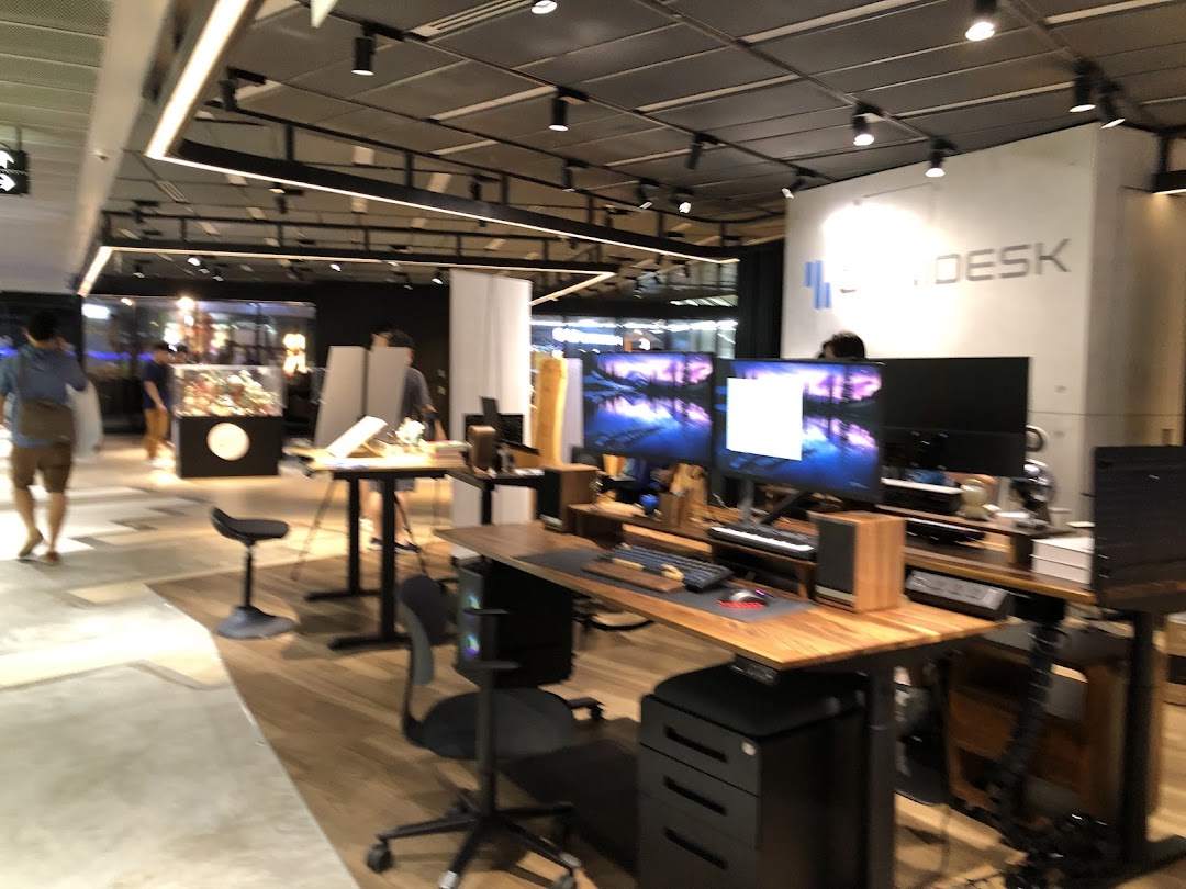 An interior view of Omnidesk showcasing adjustable desks, computer setups, and ergonomic chairs in a modern showroom.