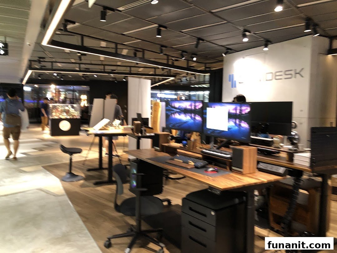 An interior view of Omnidesk showcasing adjustable desks, computer setups, and ergonomic chairs in a modern showroom.