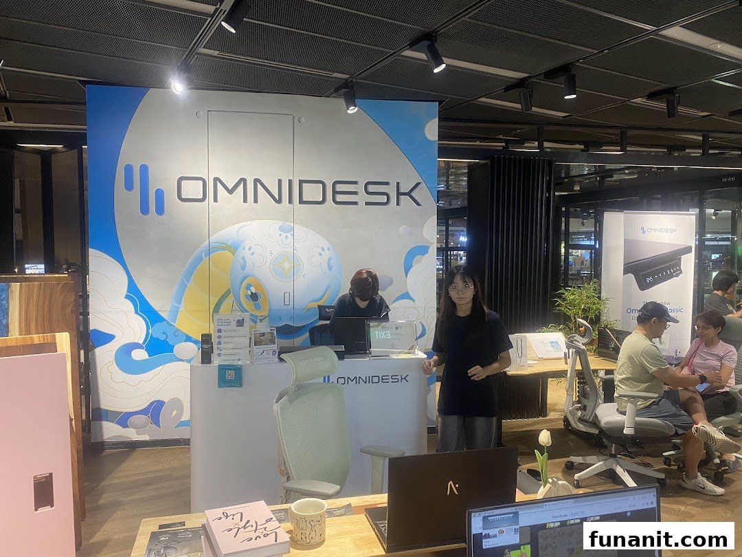 Interior view of Omnidesk Funan Mall, showcasing ergonomic desks and chairs with staff assisting customers.
