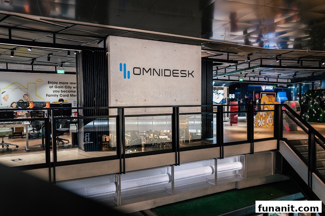 An interior view of Omnidesk, showcasing ergonomic desks, gaming setups, and the brand's prominent logo.