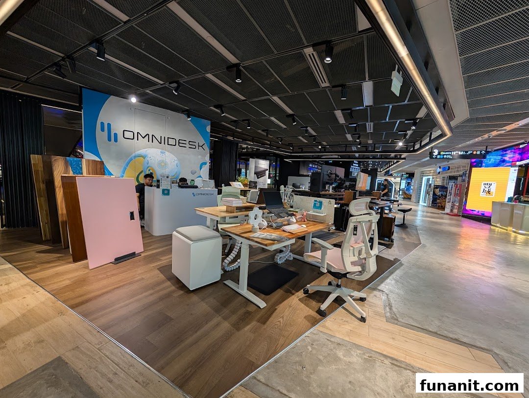 Interior view of Omnidesk Funan Mall, showcasing ergonomic standing desks, office chairs, and a reception area.