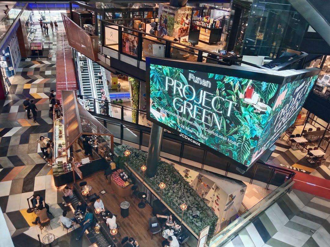 Vibrant multi-level mall interior featuring a large digital display, bustling cafe, and diverse retail spaces.