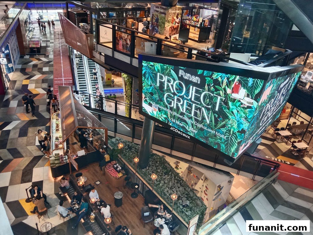 Vibrant multi-level mall interior featuring a large digital display, bustling cafe, and diverse retail spaces.
