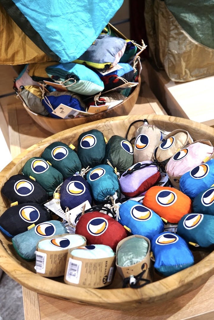 Colorful, compact outdoor gear, possibly eco-bags or hammocks, displayed in wooden bowls at Outdoor Life.