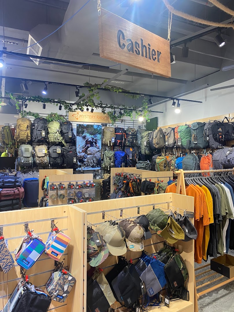 Interior view of Outdoor Life shop displaying a wide range of backpacks, apparel, and outdoor accessories.