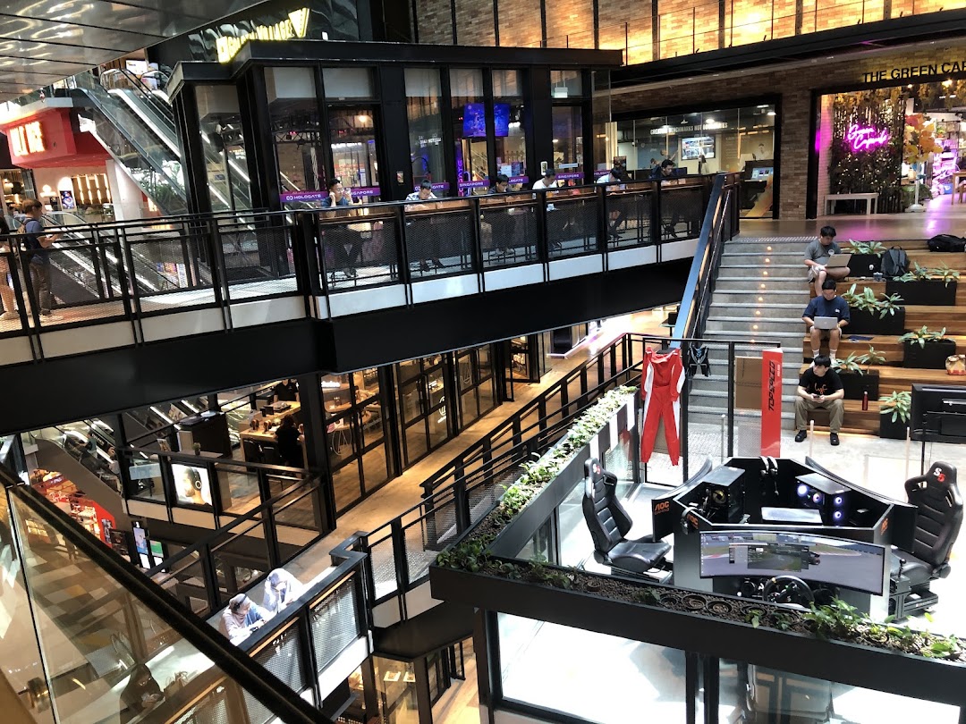 A dynamic multi-level mall interior featuring shops, escalators, and a prominent racing simulator display.