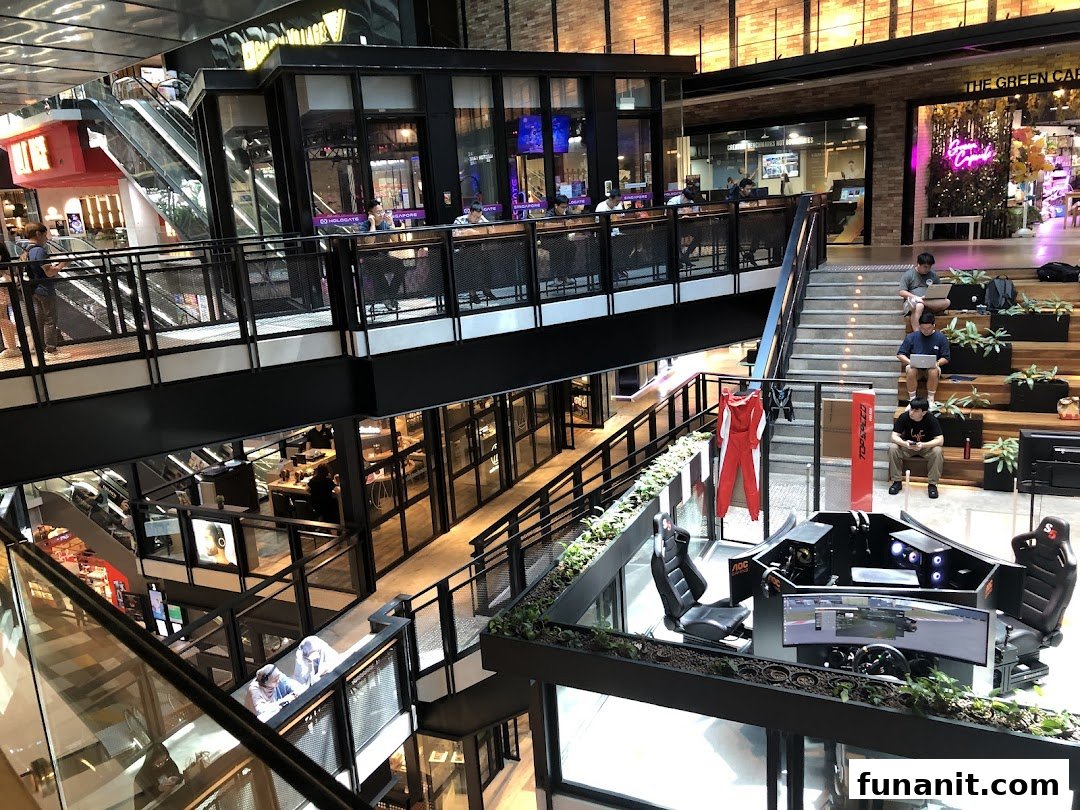 A dynamic multi-level mall interior featuring shops, escalators, and a prominent racing simulator display.