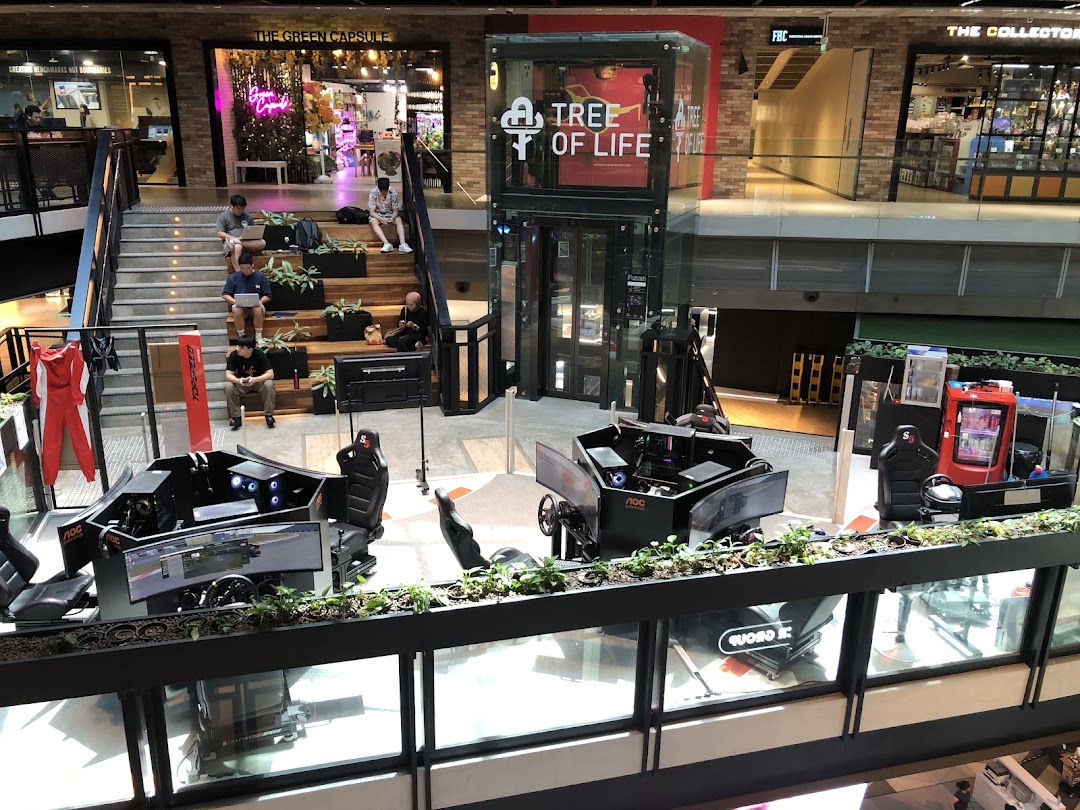 A multi-level mall interior featuring gaming simulation setups, escalators, and various retail shops.