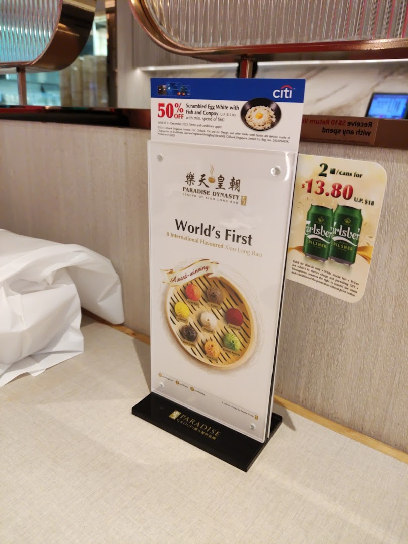 A table stand displaying Paradise Dynasty's signature 8-flavoured Xiao Long Bao and current promotions.