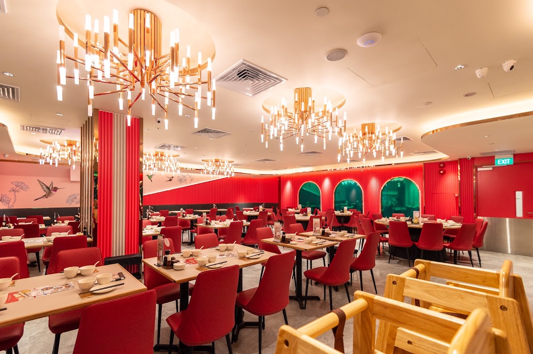 A vibrant, spacious dining room at Paradise Dynasty with red chairs, modern chandeliers, and set tables.