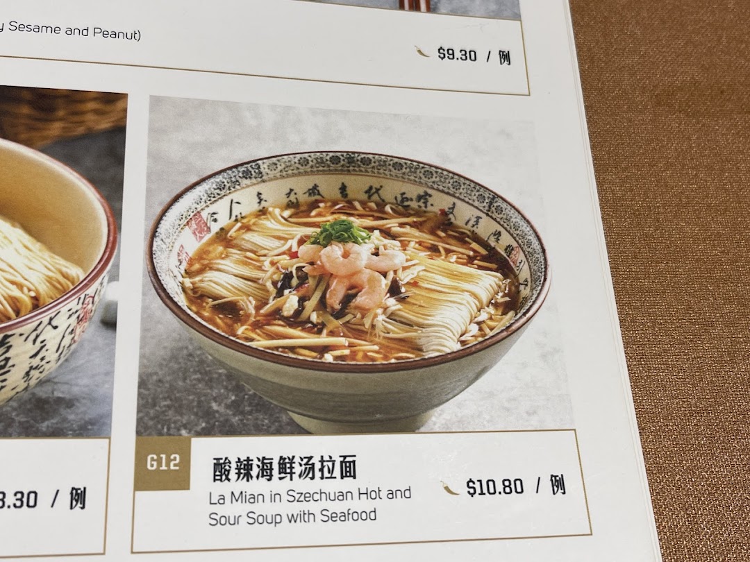 Close-up of a menu page featuring a bowl of Szechuan Hot and Sour Soup with Seafood La Mian.