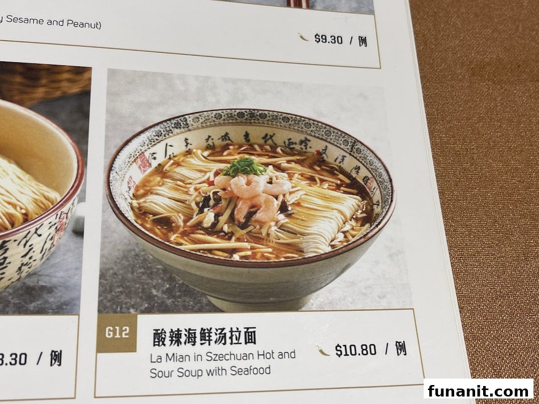 Close-up of a menu page featuring a bowl of Szechuan Hot and Sour Soup with Seafood La Mian.