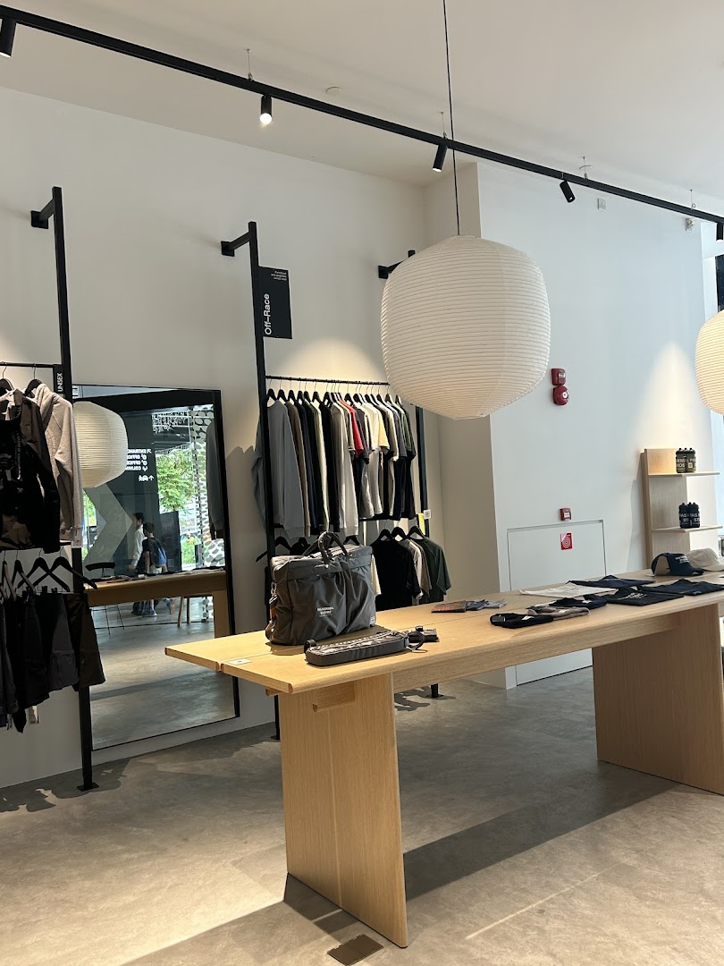 A modern retail interior featuring cycling apparel on racks, a wooden display table, and a large paper lantern.