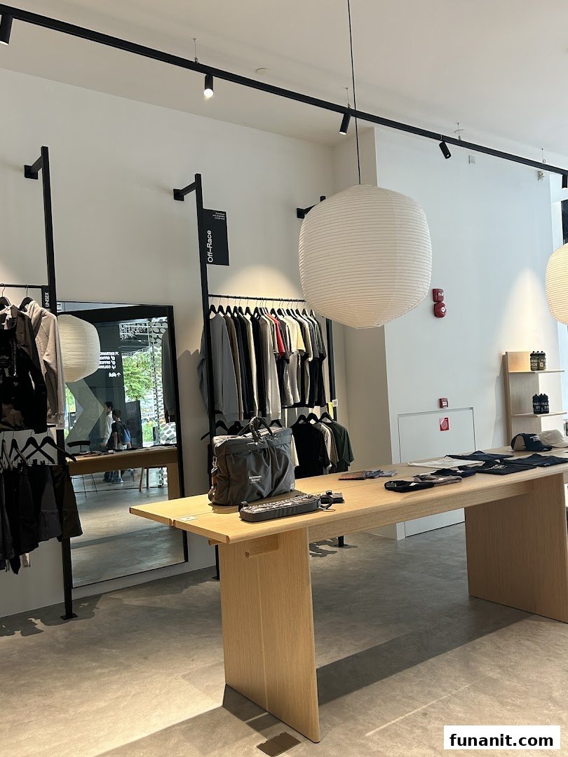 A modern retail interior featuring cycling apparel on racks, a wooden display table, and a large paper lantern.