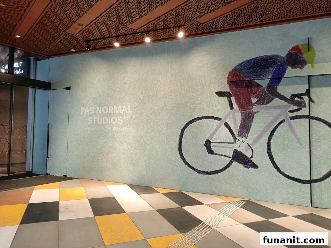 The entrance of Pas Normal Studios Singapore featuring a large cyclist mural and brand signage.