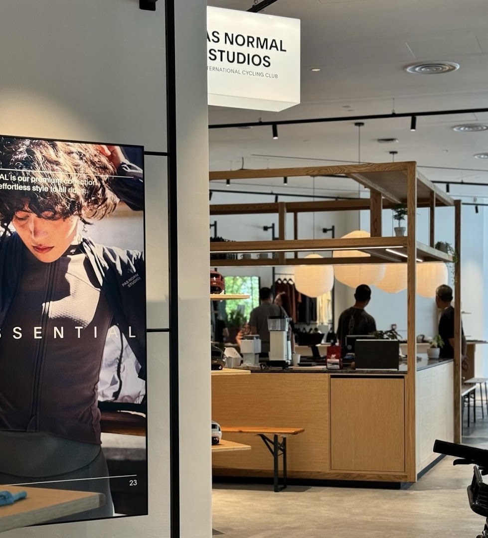 Interior view of Pas Normal Studios, featuring a counter, customers, and a large cycling apparel display.