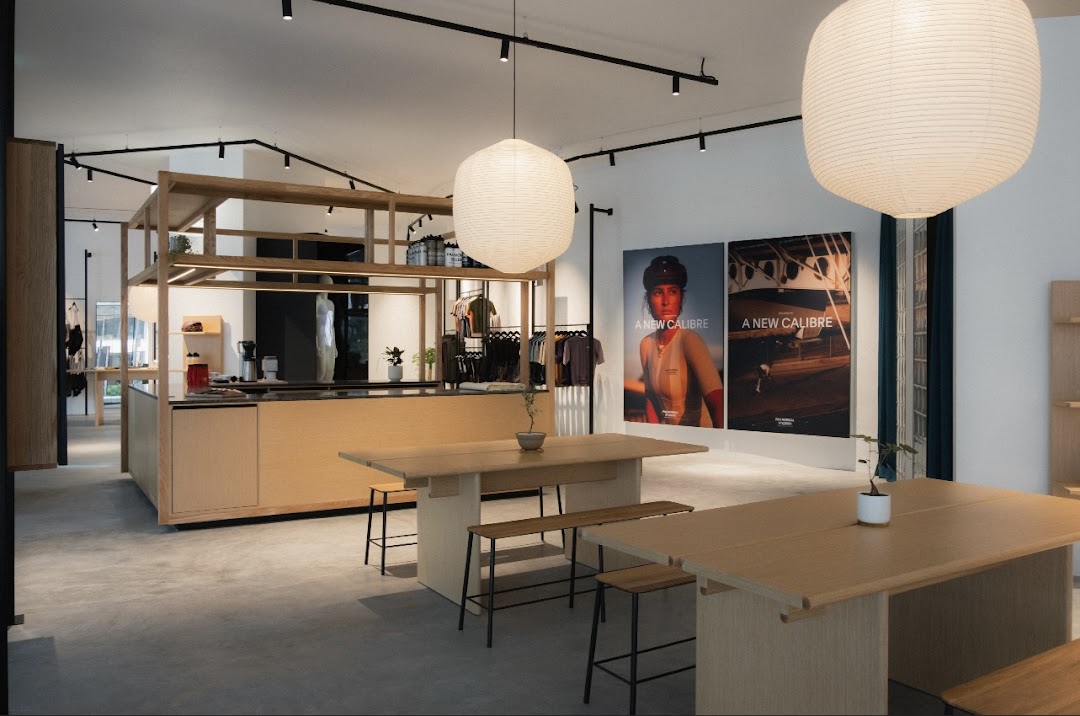 Spacious and modern interior of Pas Normal Studios, featuring apparel displays, communal tables, and large posters.
