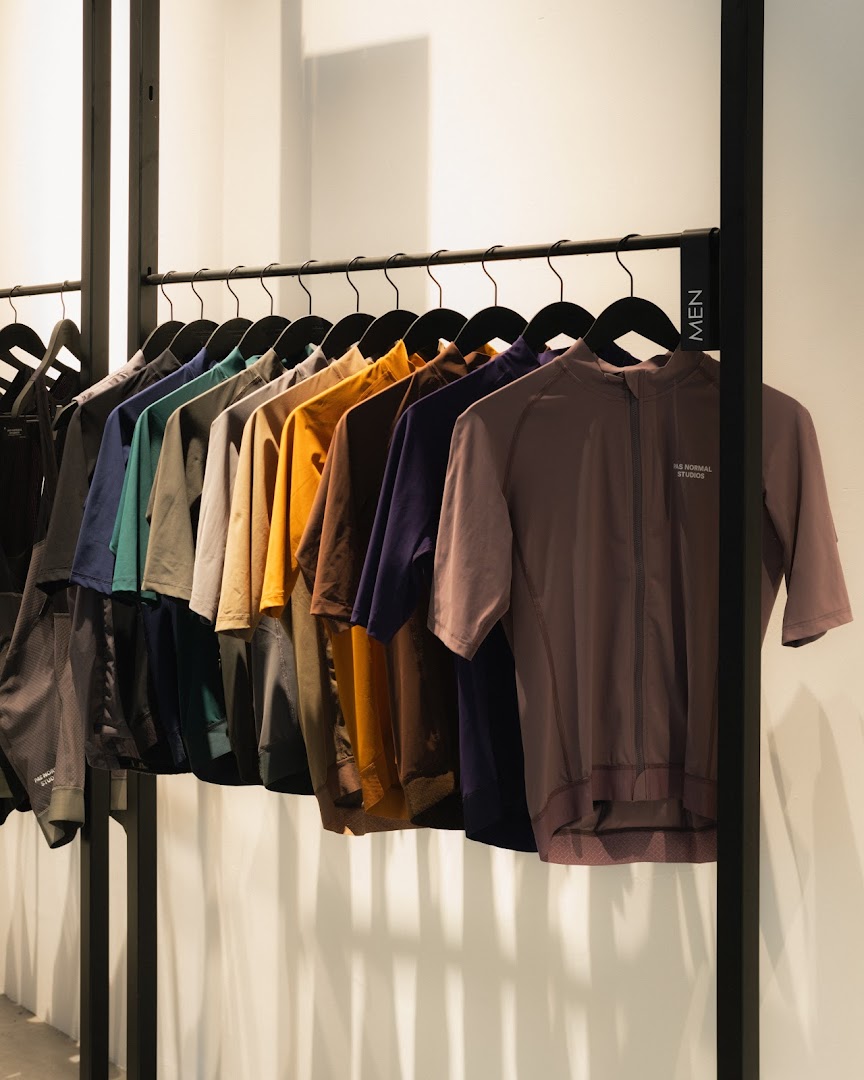 A rack of men's performance cycling apparel in various colors inside Pas Normal Studios.
