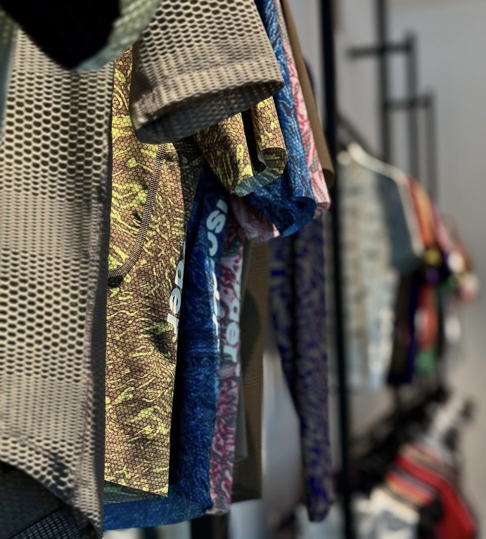 Close-up of colorful, patterned cycling apparel hanging on a rack inside Pas Normal Studios.