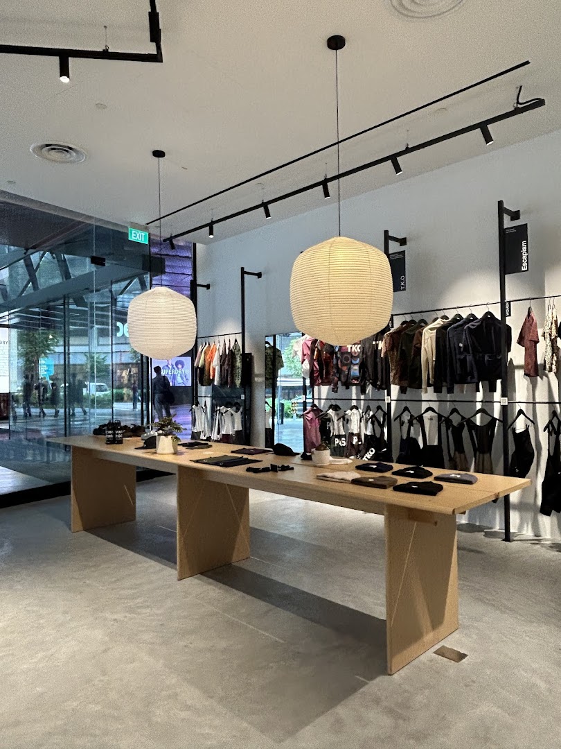 Interior view of Pas Normal Studios Singapore, featuring clothing displays and a central table.