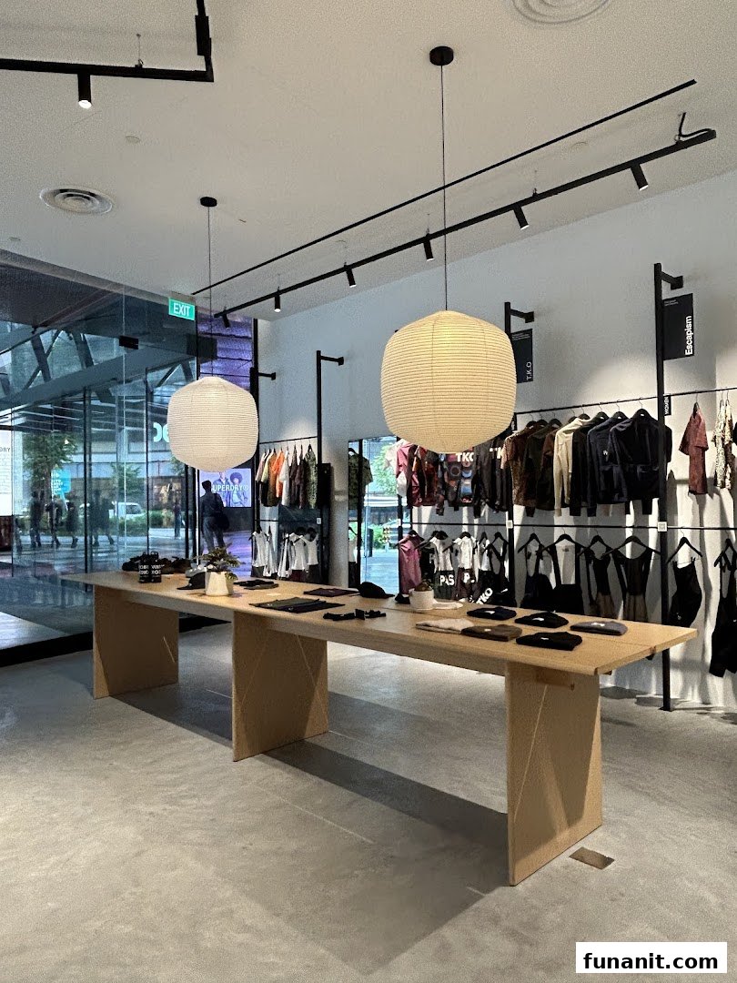 Interior view of Pas Normal Studios Singapore, featuring clothing displays and a central table.