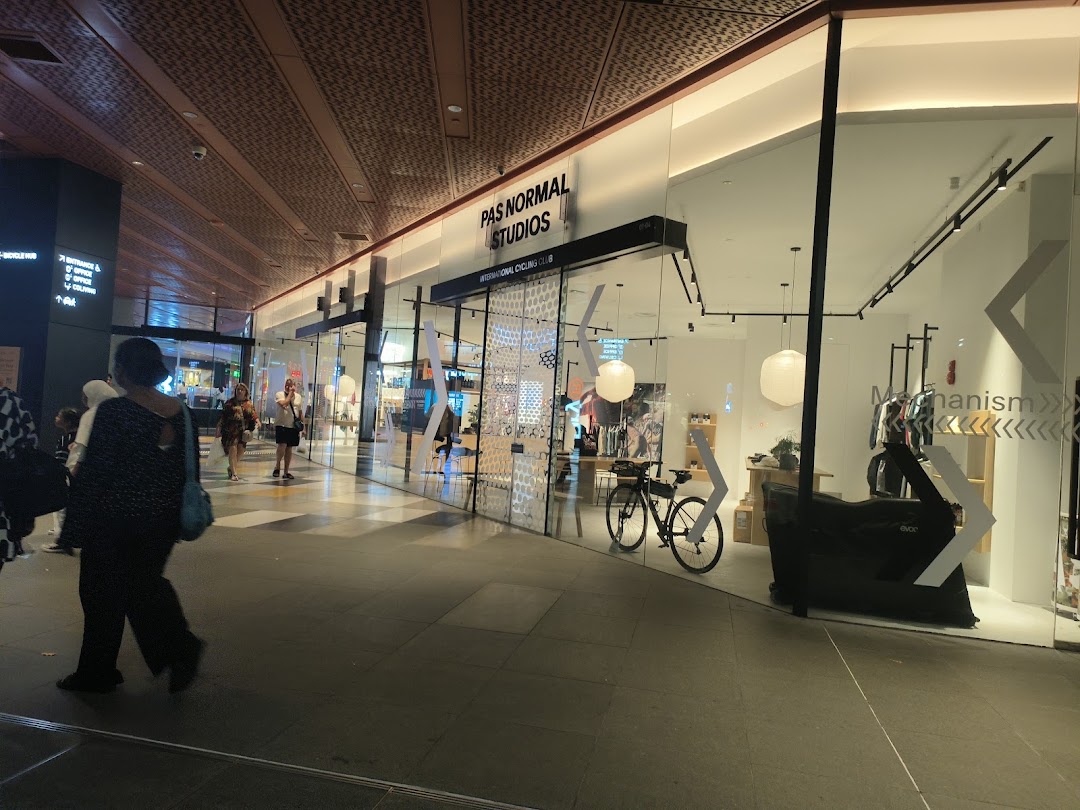 The shopfront of Pas Normal Studios, an international cycling club and apparel store, in a modern mall.