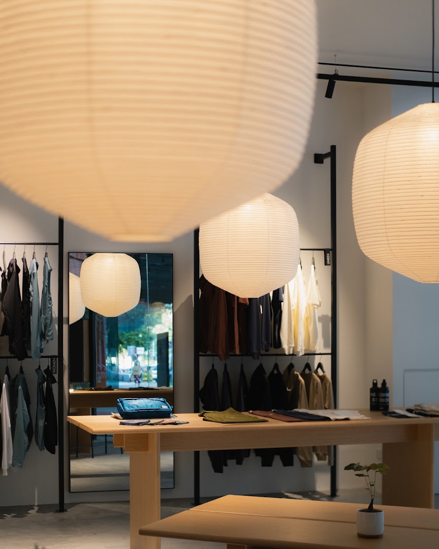 Interior view of Pas Normal Studios, showcasing minimalist design, clothing racks, and display tables with apparel.