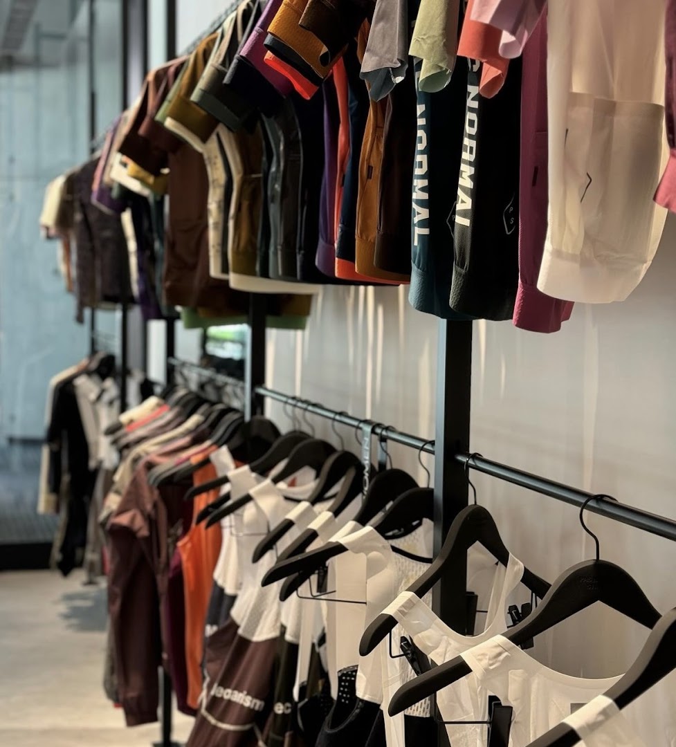Colorful cycling apparel and gear displayed on racks inside Pas Normal Studios Singapore.