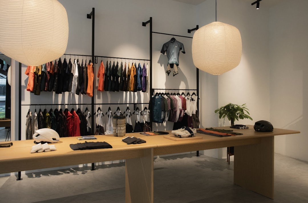 Interior of Pas Normal Studios, featuring cycling apparel displayed on racks and a central table.