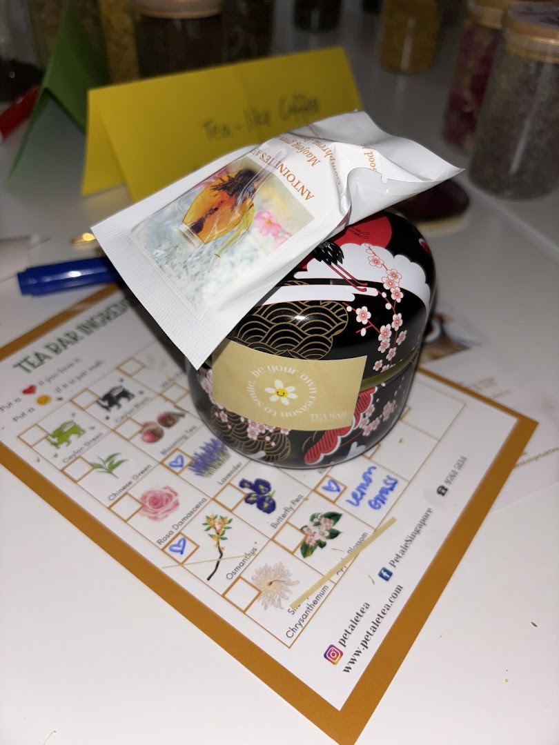 A beautifully designed tea tin, a tea sachet, and a 'Tea Bar Ingredients' list for custom blending.