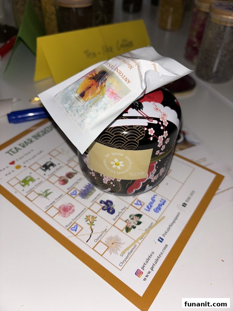 A beautifully designed tea tin, a tea sachet, and a 'Tea Bar Ingredients' list for custom blending.