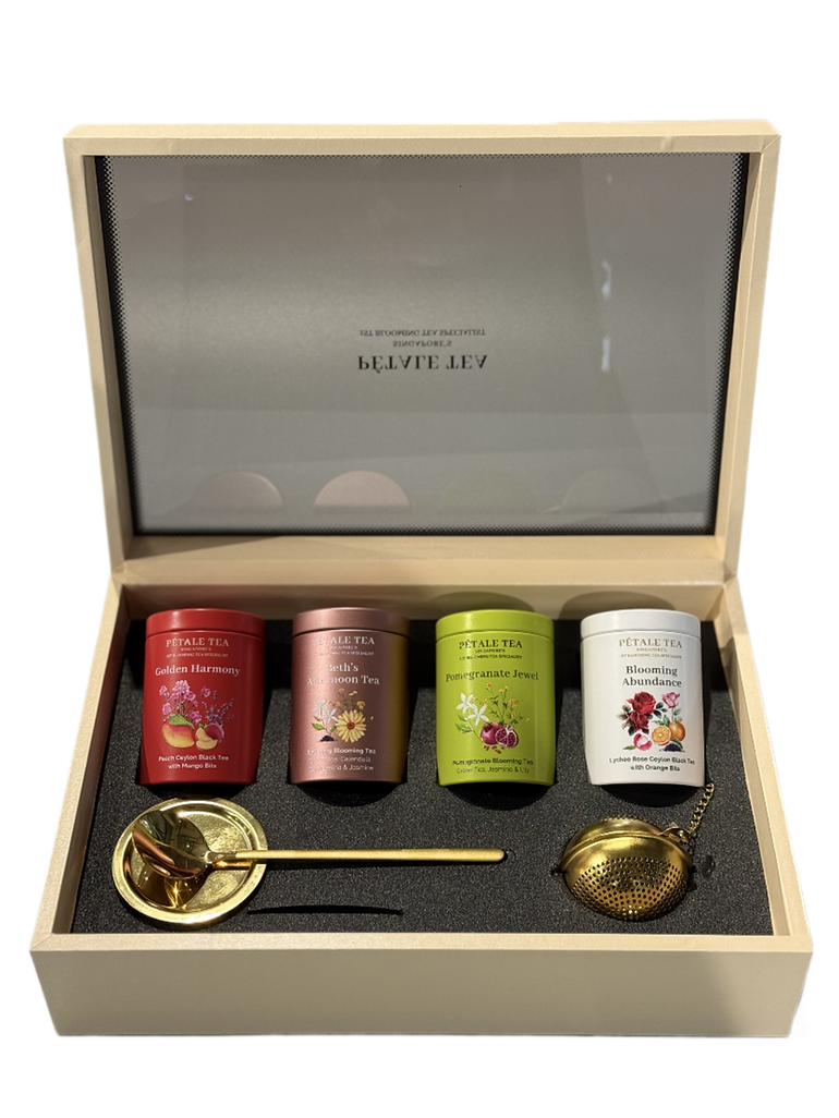 A beautifully presented Pétale Tea gift set featuring four tea tins, a golden spoon, and a tea infuser.