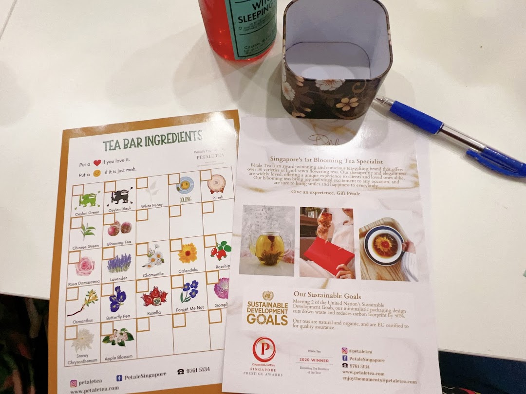 A table displays Pétale Tea's 'Tea Bar Ingredients' chart, promotional flyer, a pen, and a tea box.